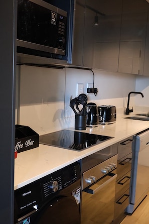 Eine moderne Küche mit Geschirrspüler, einer Kaffeestation und einer Mikrowelle.