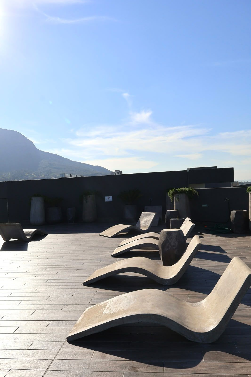 Eine Dachterrasse mit modernen Lounge-Möbeln und Topfpflanzen.