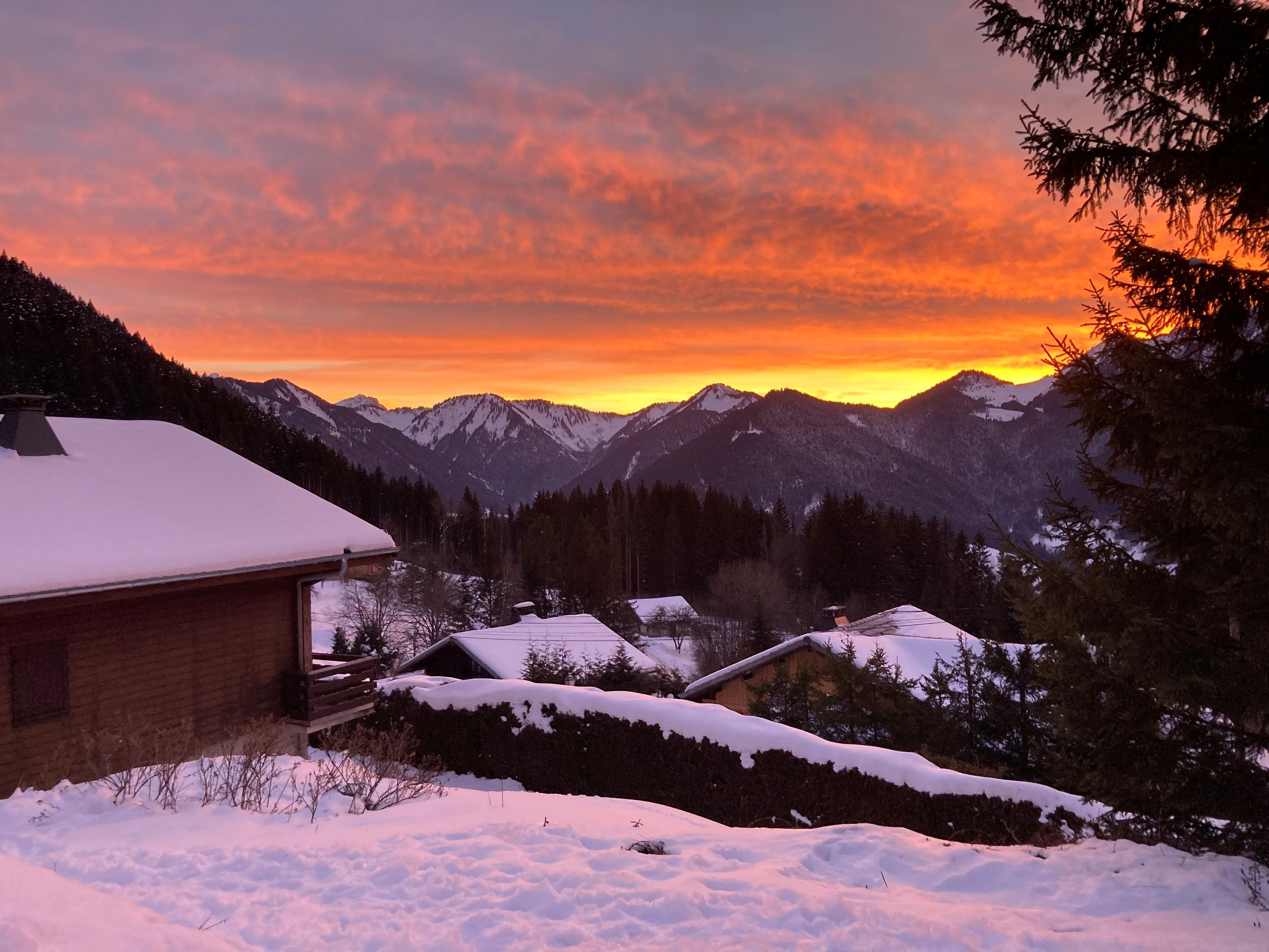 A snow-covered mountain landscape with a wooden cabin and a house in the foreground.