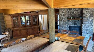 A rustic wooden interior with a stone fireplace, wooden dining table, and chairs.