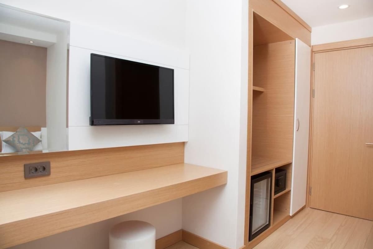 A modern bathroom with a built-in TV, wooden vanity, and a shower area.