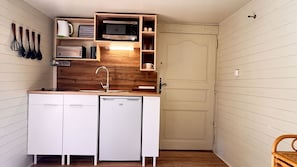 Une cuisine compacte équipée d’un four à micro-ondes encastré, d’un évier et d’un lave-vaisselle.