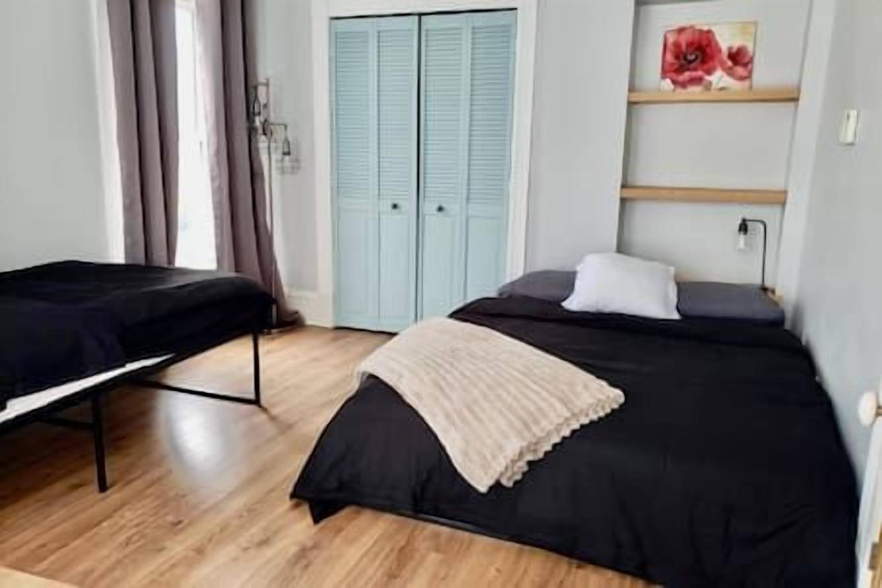 Une chambre avec deux lits, une armoire et un tableau au mur.