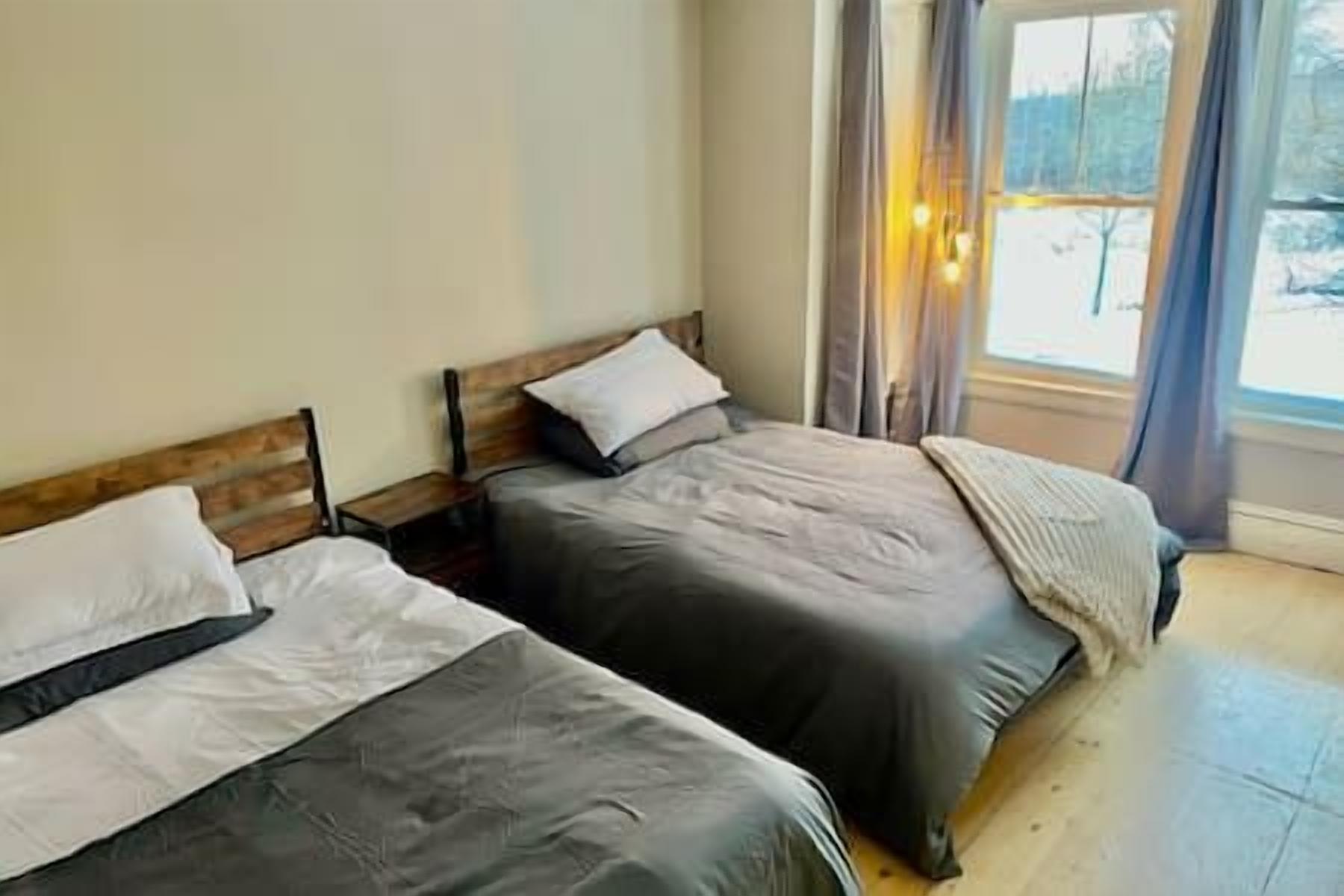 Une chambre avec deux lits, une fenêtre avec des rideaux et une vue sur l’extérieur.