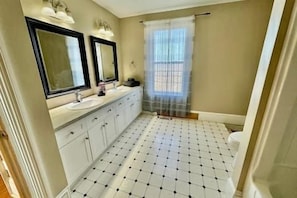 Een badkamer met betegelde vloer, toilet, wastafel met spiegel en douchegordijn.