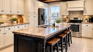 A kitchen with white cabinets, a granite countertop, a stainless steel refrigerator, a built-in oven, and a large window.