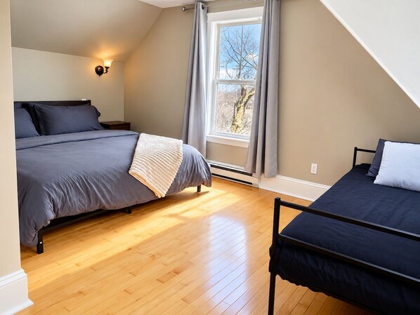 Une chambre avec deux lits, une fenêtre avec des rideaux et un luminaire fixé au mur.