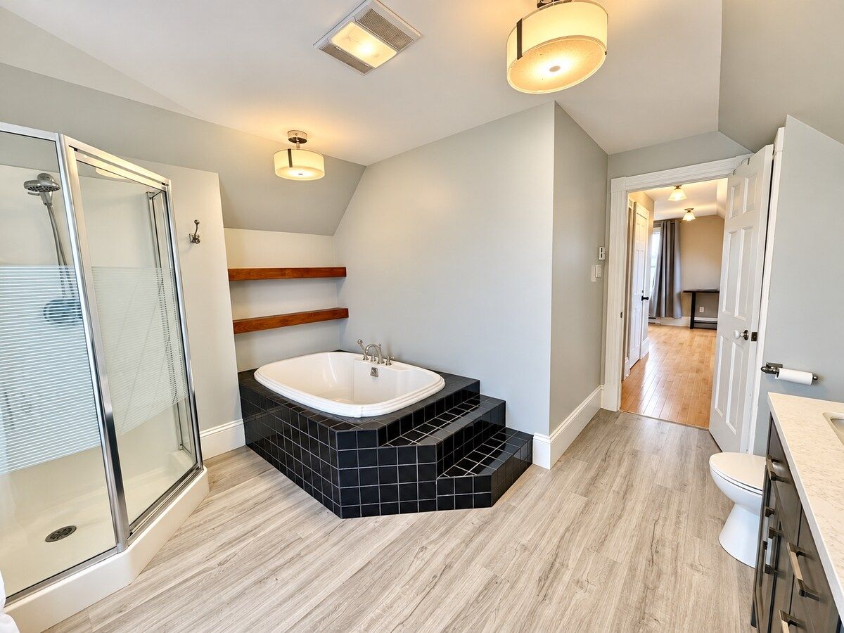 Une salle de bain moderne dotée d’une douche à parois de verre, d’une baignoire sur pieds et d’une douche à l’italienne.