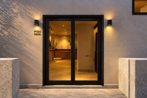 A hotel entrance with a glass door, a reception area visible inside, and a sign above the door. - SANDANKYO HOTEL NAMPO (Akiōta)