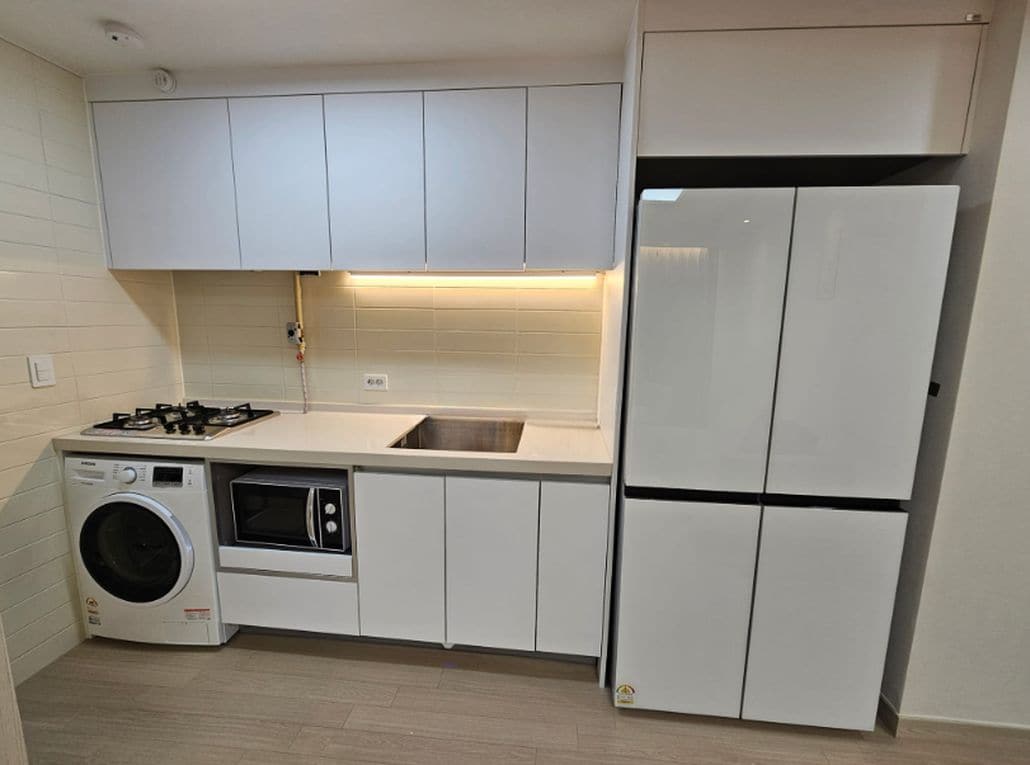 A compact kitchen with a gas stove, microwave, and a built-in washing machine.