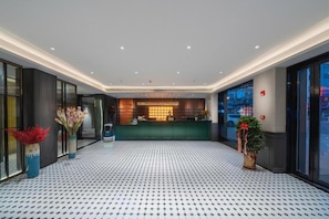 Un hall d’hôtel avec un comptoir d’accueil, un sol à motifs et une grande fenêtre.