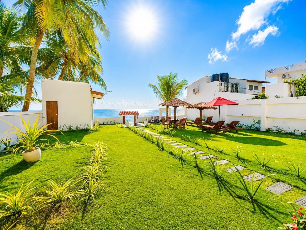 A well-maintained lawn with a pathway leading to a seating area with umbrellas.