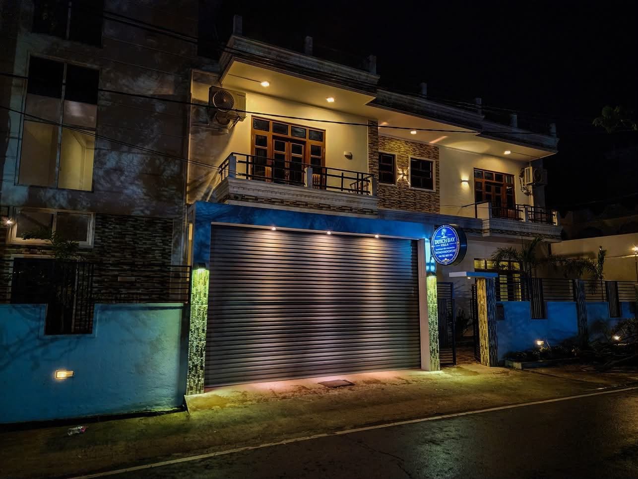 A two-story building with a garage door, a balcony, and a sign that reads 'Dutch Bay'.