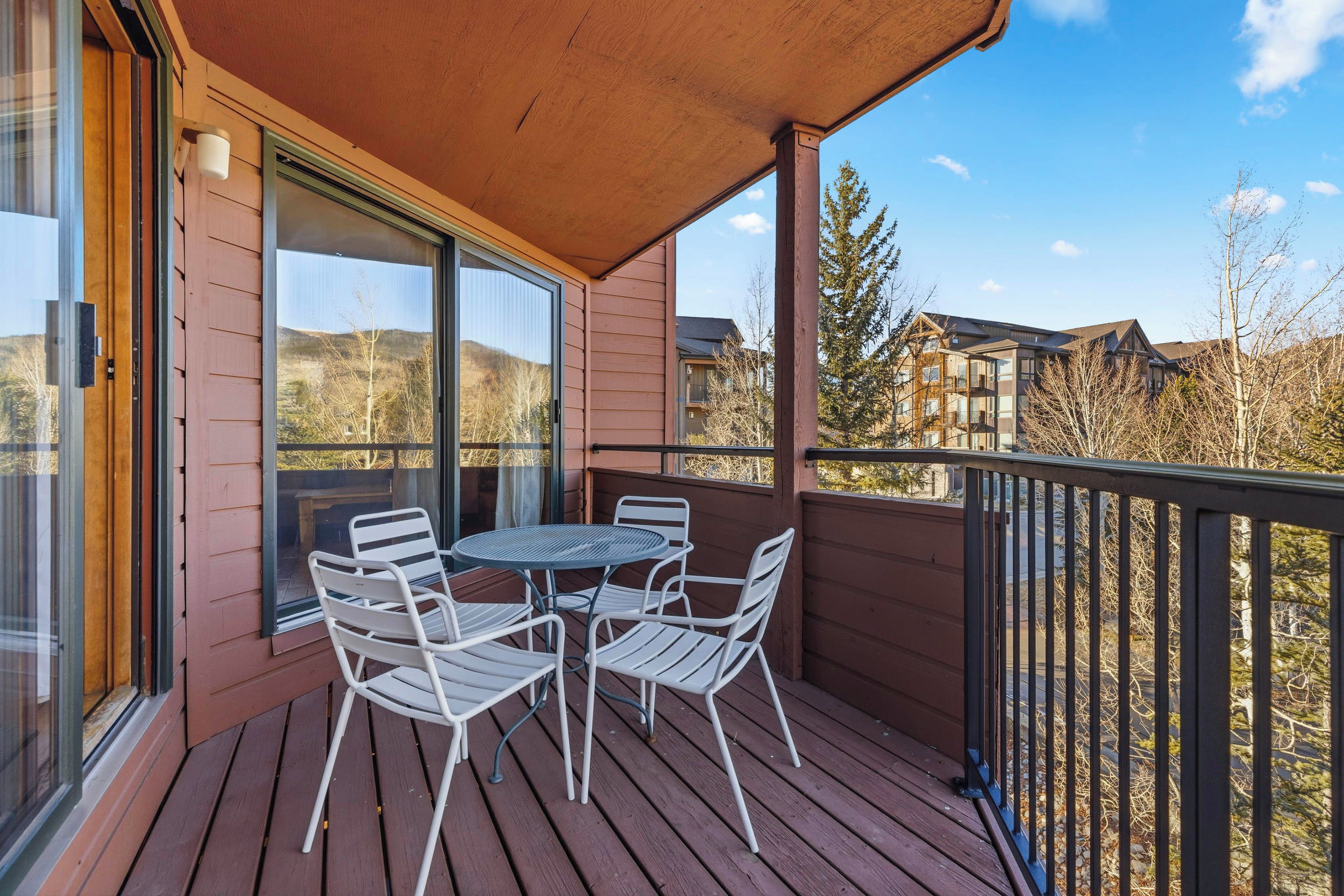 A wooden deck with a table and chairs, overlooking a residential area with houses and trees.