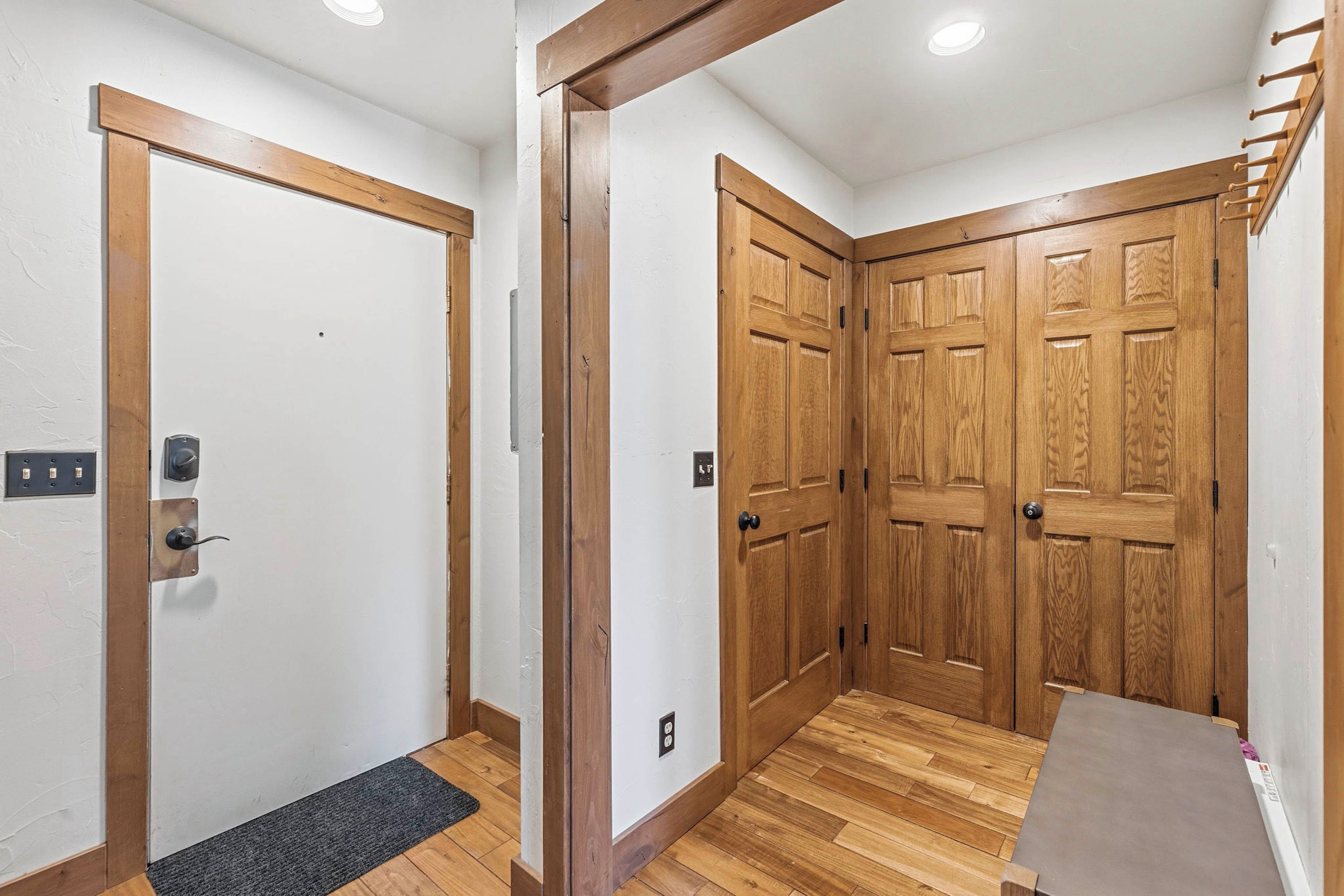 A hallway with wooden doors, a small table, and a carpeted entrance.
