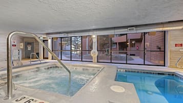 Una piscina interior con un indicador de profundidad de 3 pies, un cartel de prohibido fumar y un letrero de salvavidas para uso de emergencia.