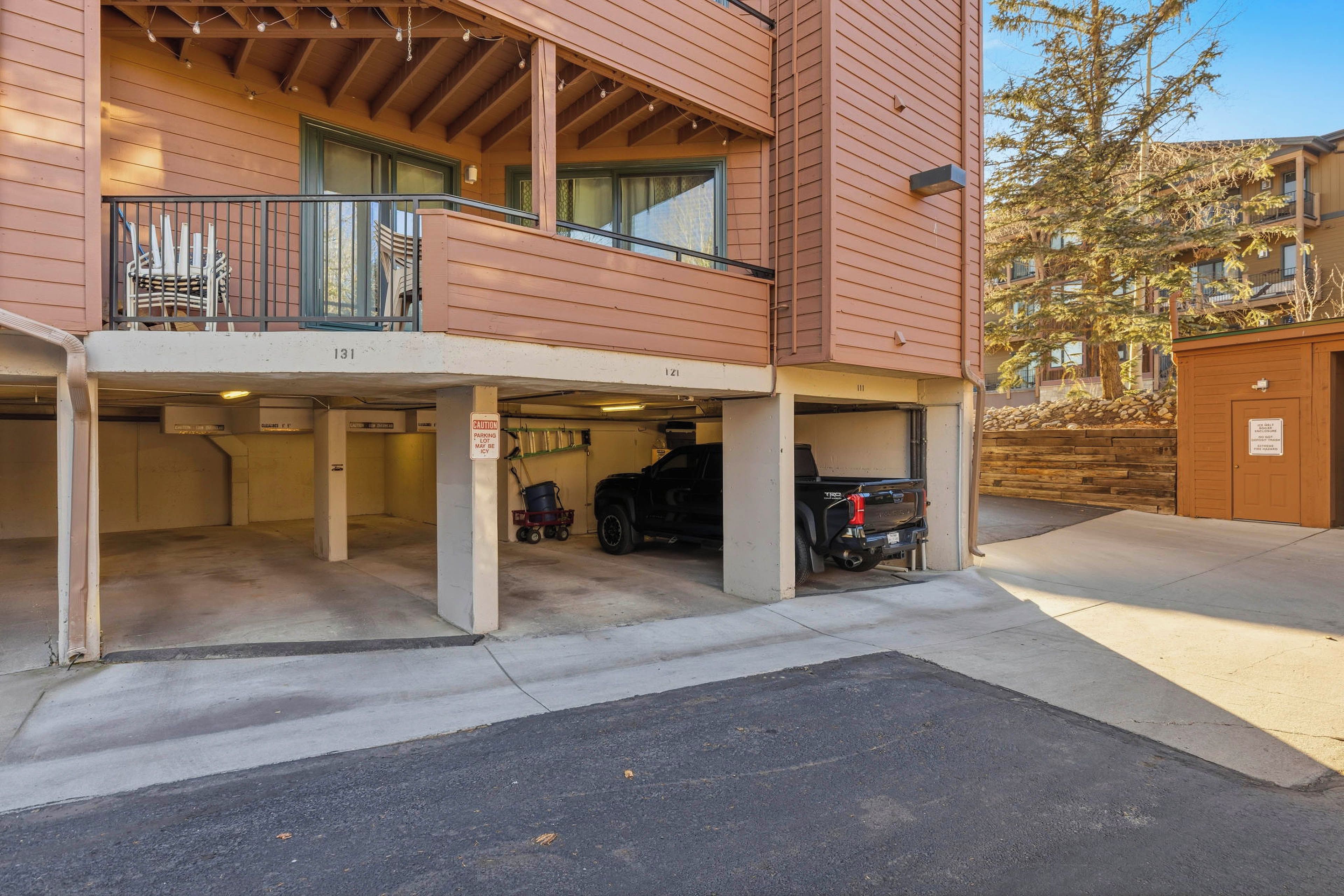 A multi-story building with a covered parking area and a vehicle inside.