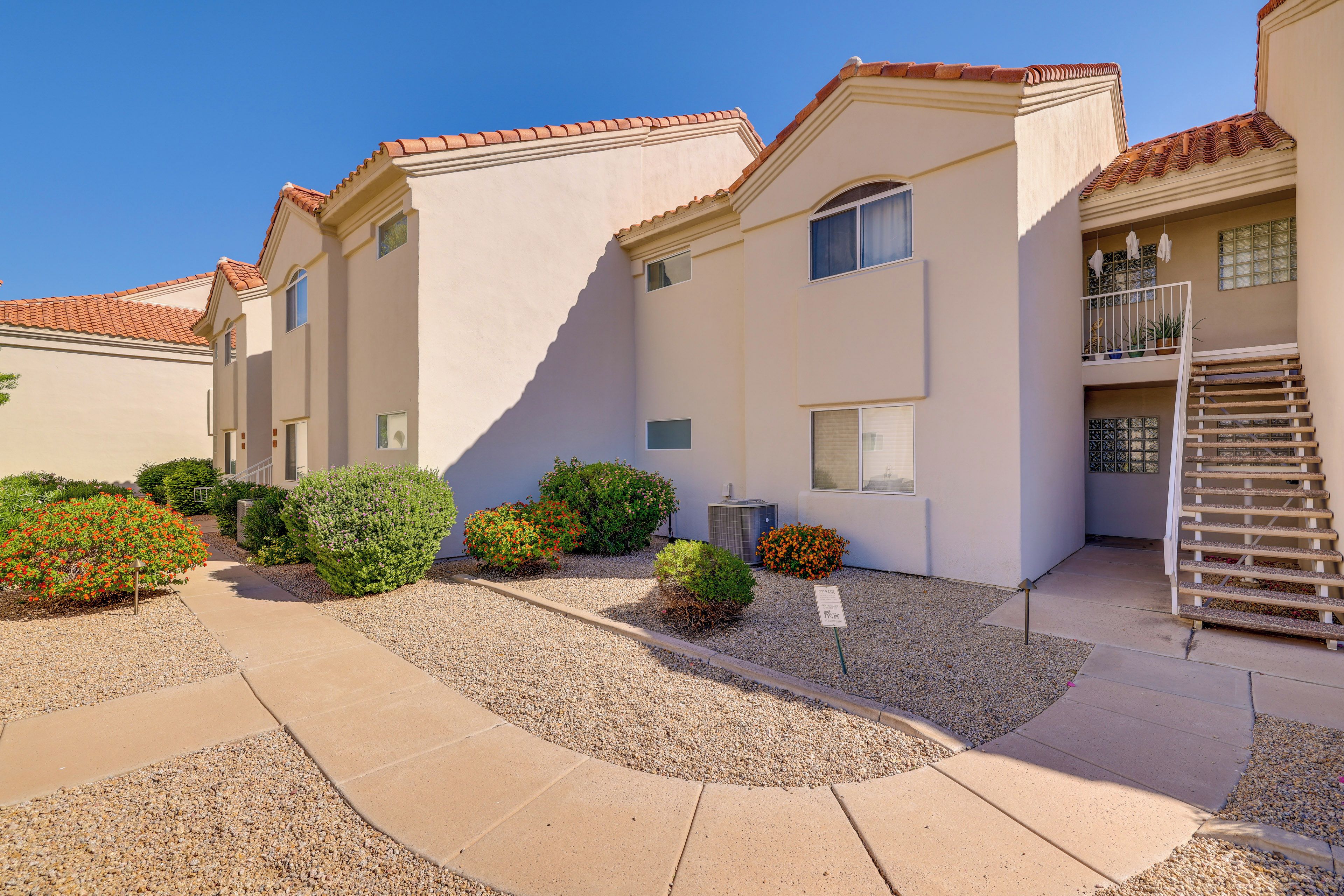 A residential building with a tiled roof, multiple windows, and a gravel pathway leading to the entrance.