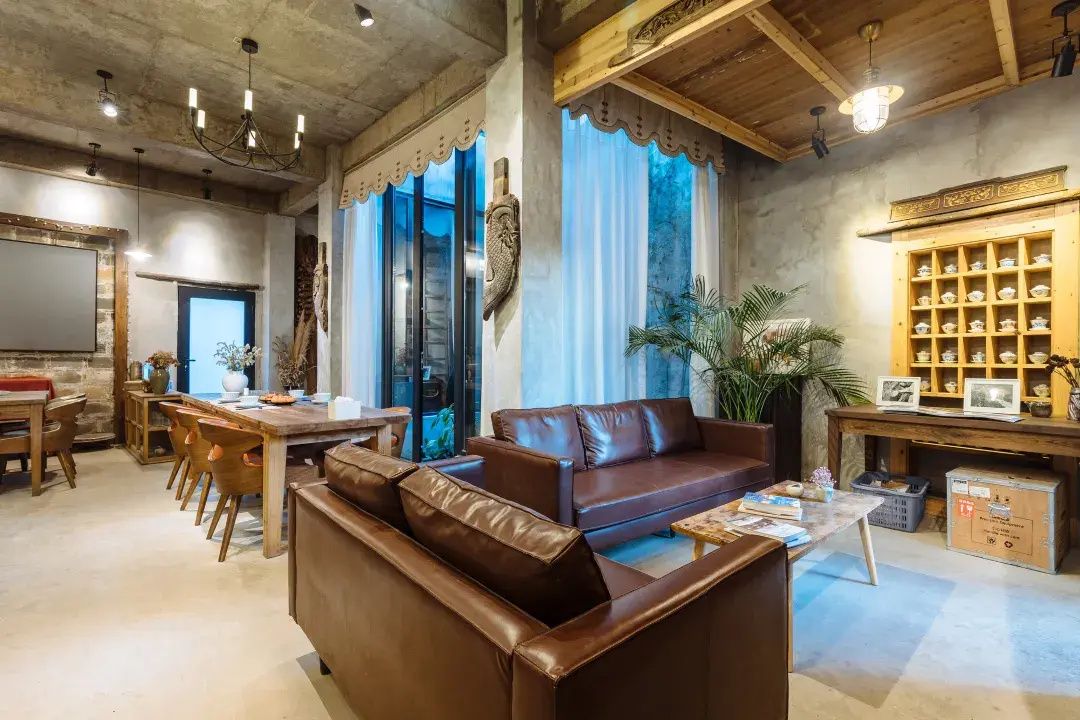 A modern living room with a leather sofa, wooden dining table, and a bookshelf.