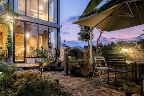 An outdoor patio area with a dining table and chairs, surrounded by potted plants and a stone pathway. - Wuyuan Jianwai Rill Wild Homestay (Shangrao)