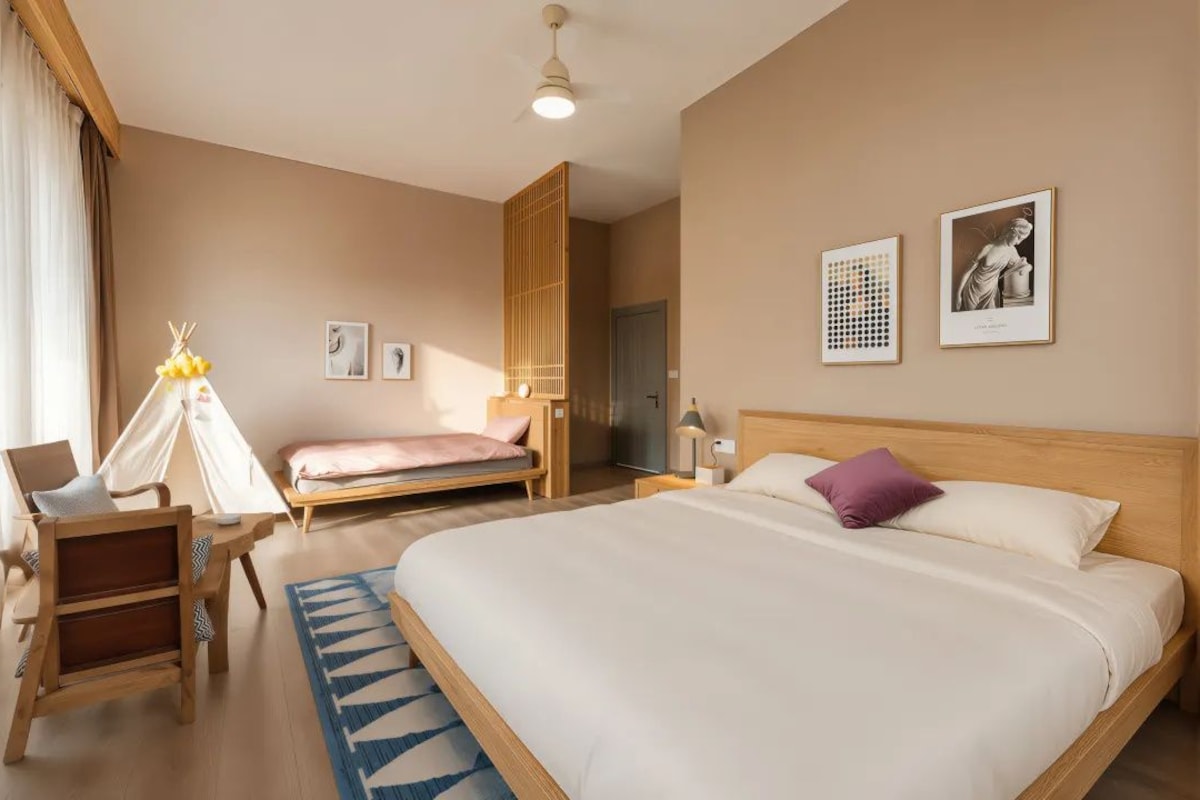 A hotel room with a large bed, a chair, a small desk, a wardrobe, and a door.