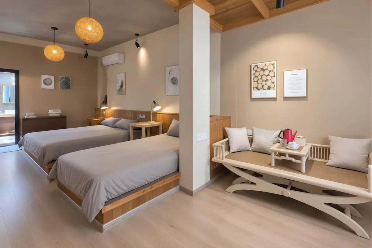 A hotel room with two beds, a dining table, and a seating area.