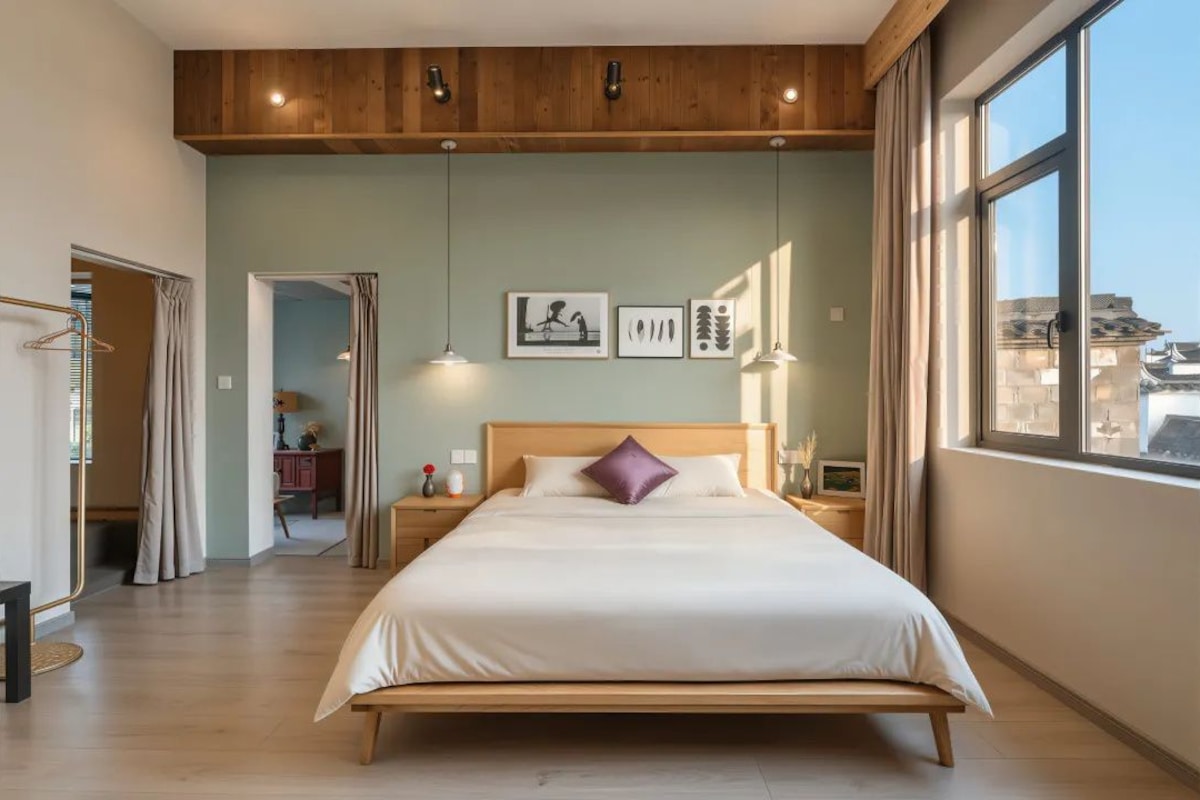 A bedroom with a large bed, wooden headboard, and a view of the city through a window.