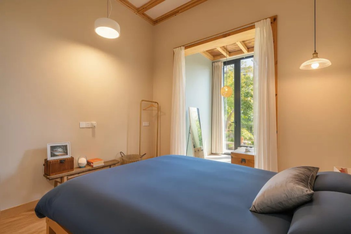 A bedroom with a bed, bedside table, and a window with curtains.