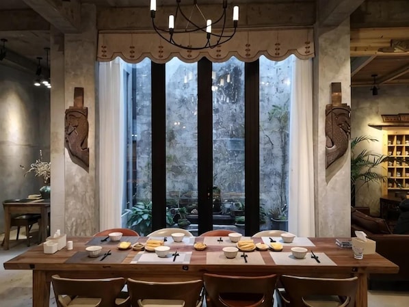 A dining area with a long table set for six, surrounded by chairs.
