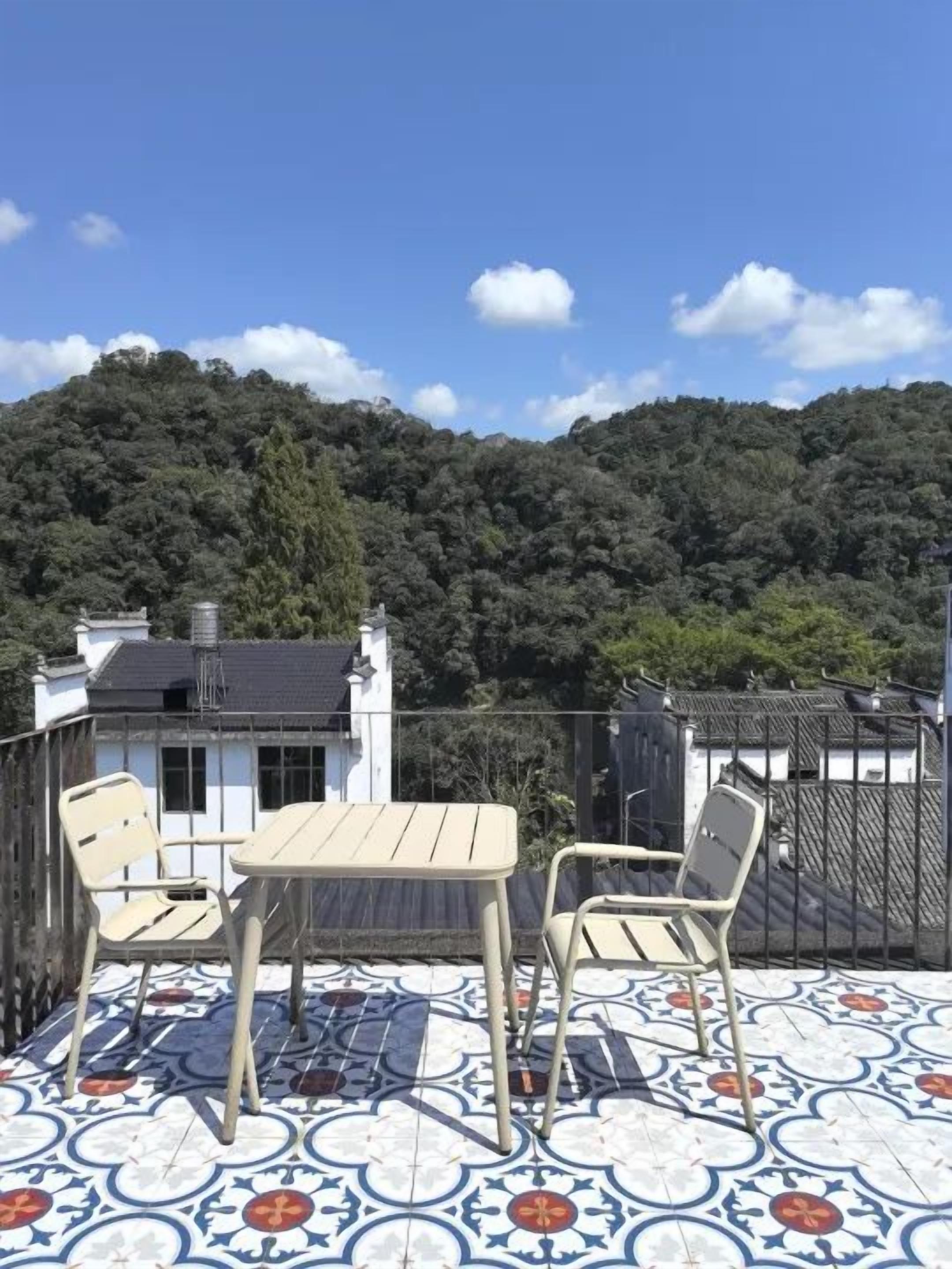 A terrace with a table and chairs, overlooking a forested hill.