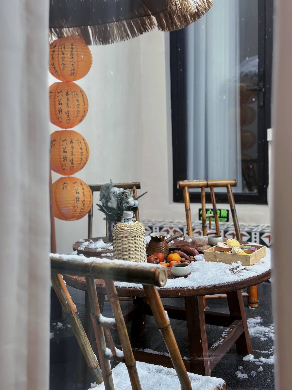 Un entorno tradicional japonés con una mesa preparada para una comida, rodeada de sillas de bambú y un techo de paja.