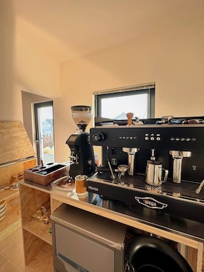 A modern kitchen with a coffee machine, a window, and a view of a building.