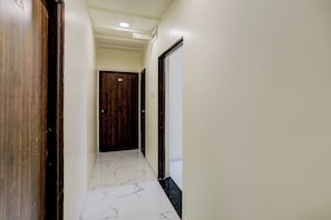 Un pasillo con piso de mármol, una puerta de madera con el número 104 y una pared blanca.