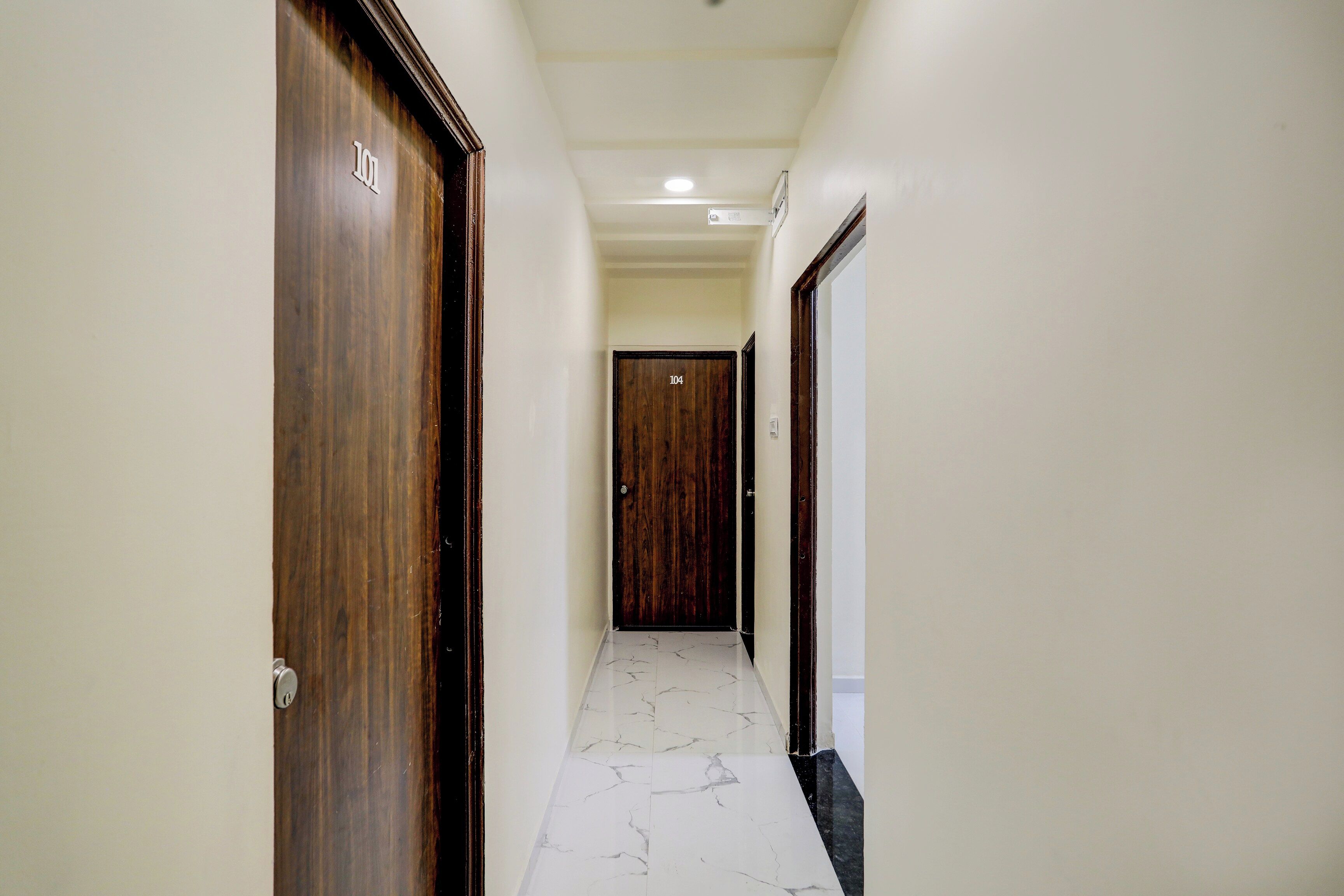 Un pasillo con puertas de madera, números 101 y 104, que dan a habitaciones.
