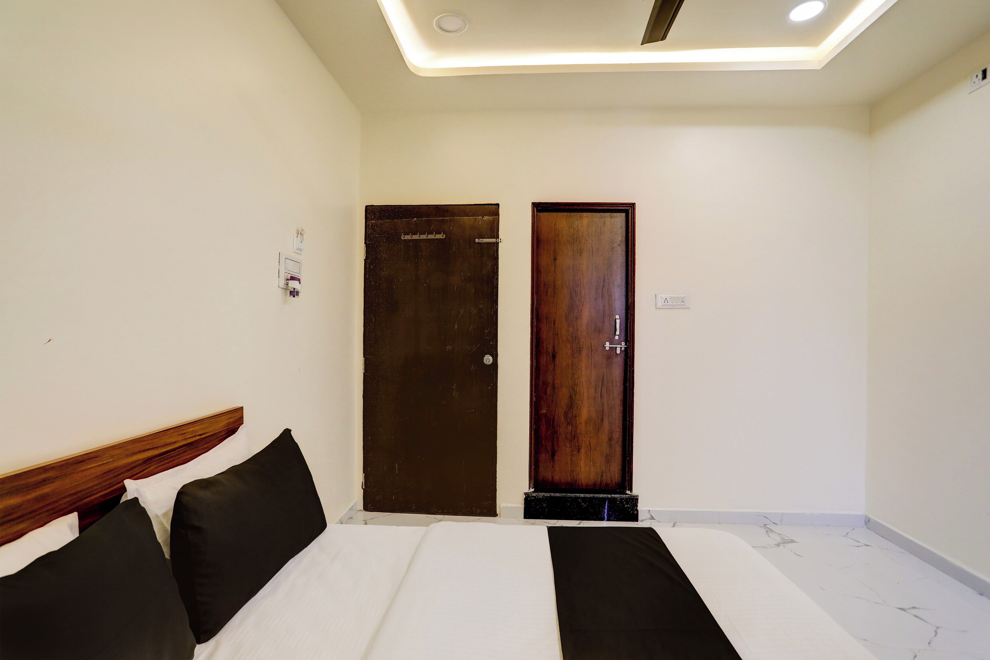 Ein Hotelzimmer mit einem Bett, zwei Türen und einer Deckenleuchte.