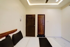Habitación de hotel con una cama, dos puertas y un aplique en el techo.
