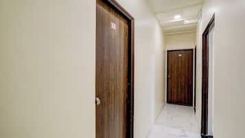 Corredor com portas de madeira, numeradas 101 e 104, e piso de mármore.