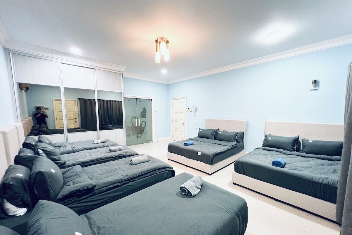 Habitació d'hotel amb diversos llits, un mirall gran i un armari.