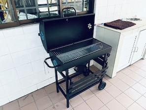 A portable grill with wheels, a window, and a tiled floor.