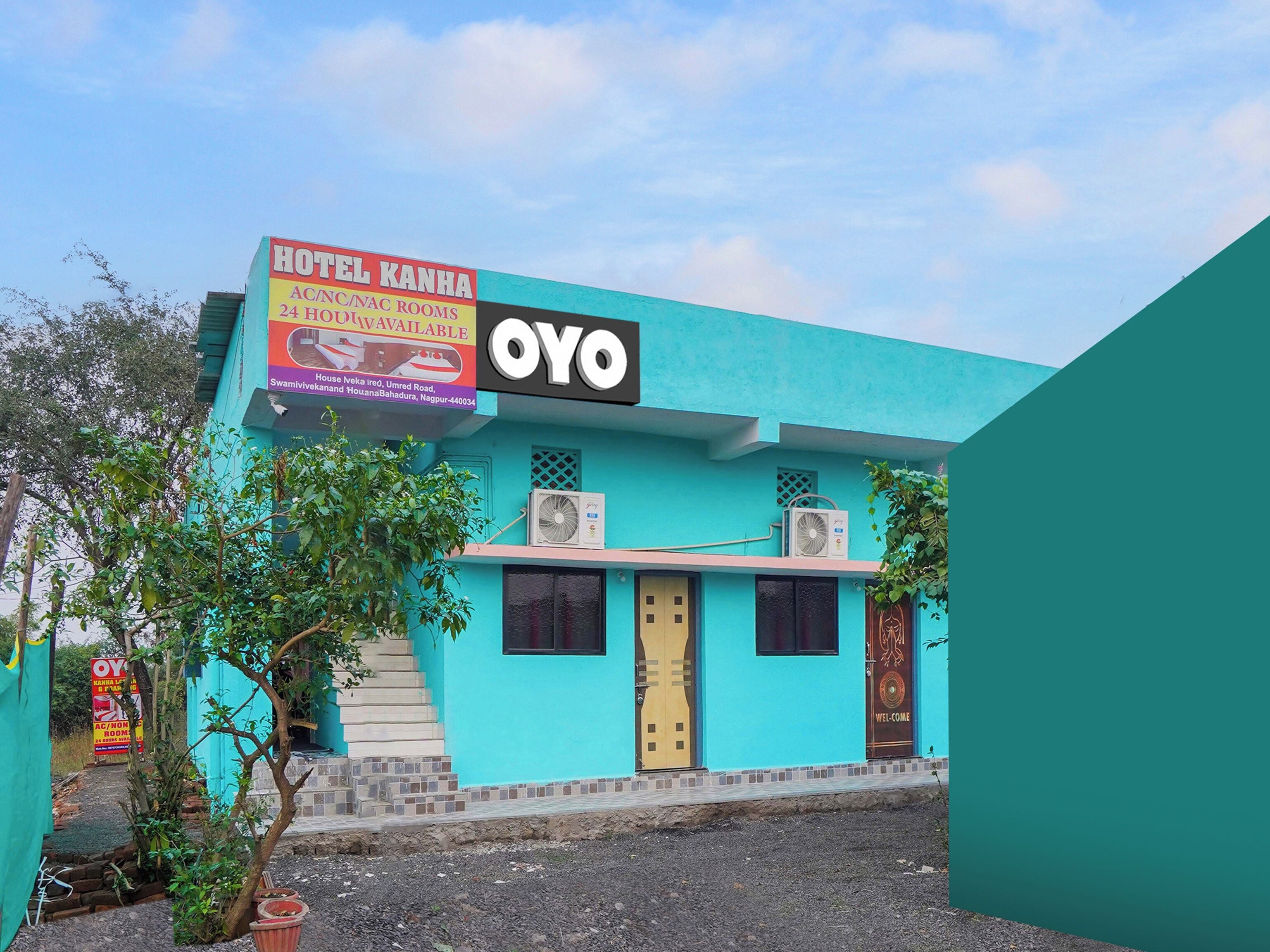Un hotel llamado 'Hotel Kanha' con un equipo de aire acondicionado y un cartel publicitario que anuncia disponibilidad las 24 horas.