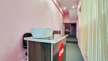 A reception area with a desk, a ceiling fan, and a door in the background.
