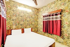 A room with floral wallpaper, a bed with white linens, and a red curtain. - Hotel O Marina Hotel (Nagpur)