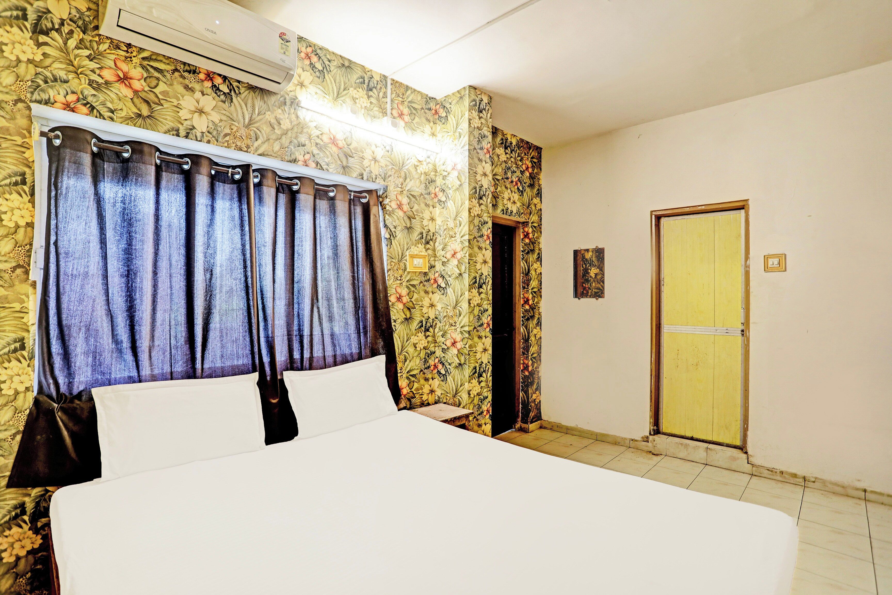 A room with a bed, a door, and floral wallpaper.