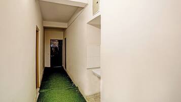 Un pasillo estrecho con alfombra verde, paredes blancas y una puerta al final.