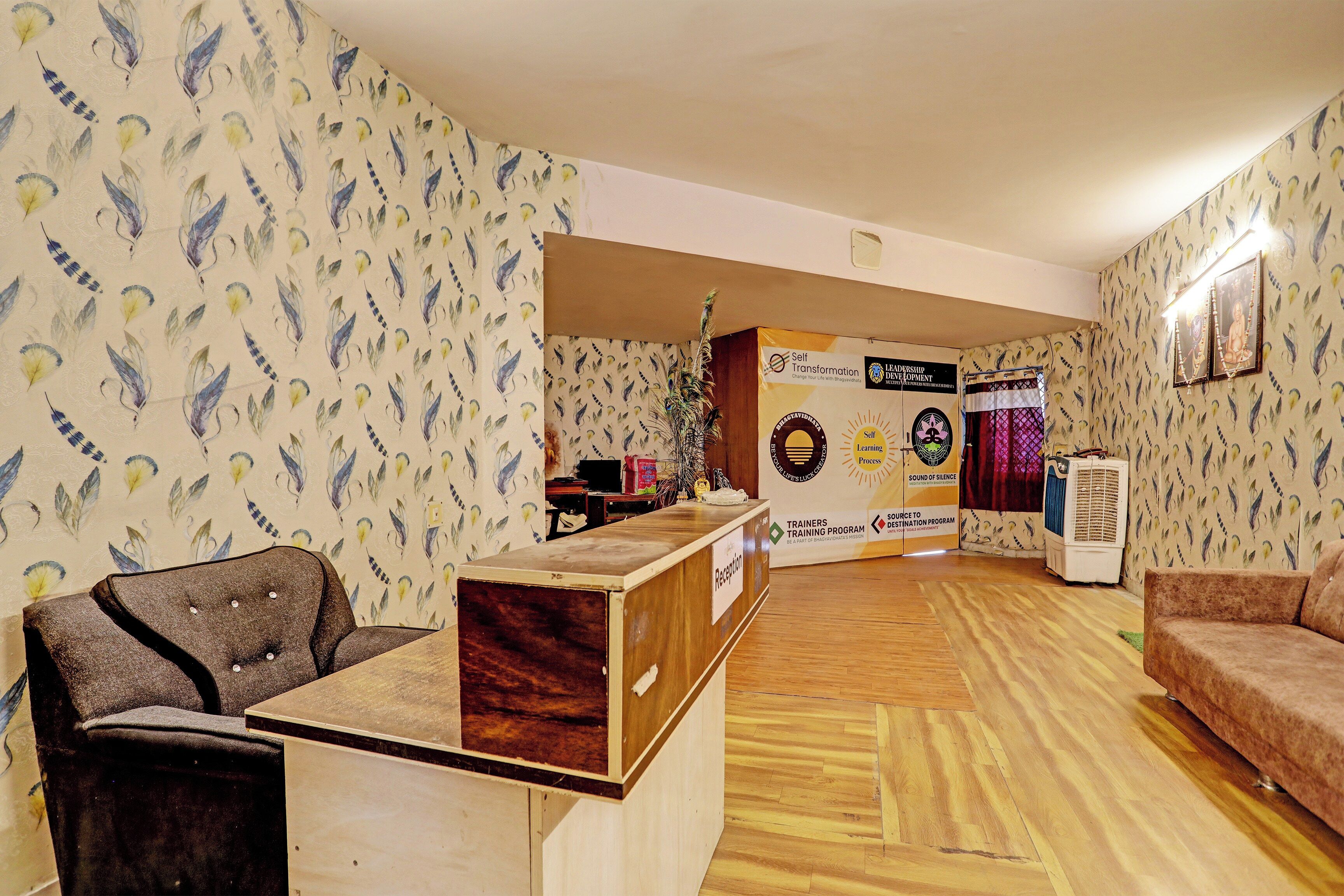 A reception area with a wooden desk, a couch, and patterned wallpaper.