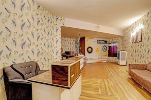 A reception area with a wooden desk, a couch, and patterned wallpaper. - Hotel O Marina Hotel (Nagpur)