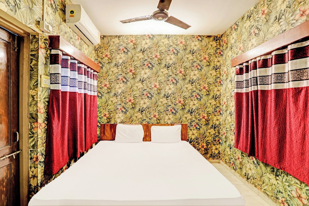 A bedroom with a bed, curtains, a ceiling fan, and floral wallpaper.