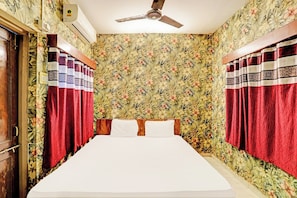 A bedroom with a bed, curtains, a ceiling fan, and floral wallpaper. - Hotel O Marina Hotel (Nagpur)