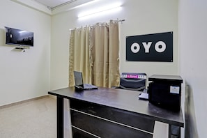 A reception desk with a laptop, a printer, and a chair. A television is mounted on the wall, and a sign with 'OYO' is visible. - Hotel O by OYO P S (Nagpur)