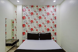 Un dormitorio con una cama, un espejo y una pared con un diseño circular.